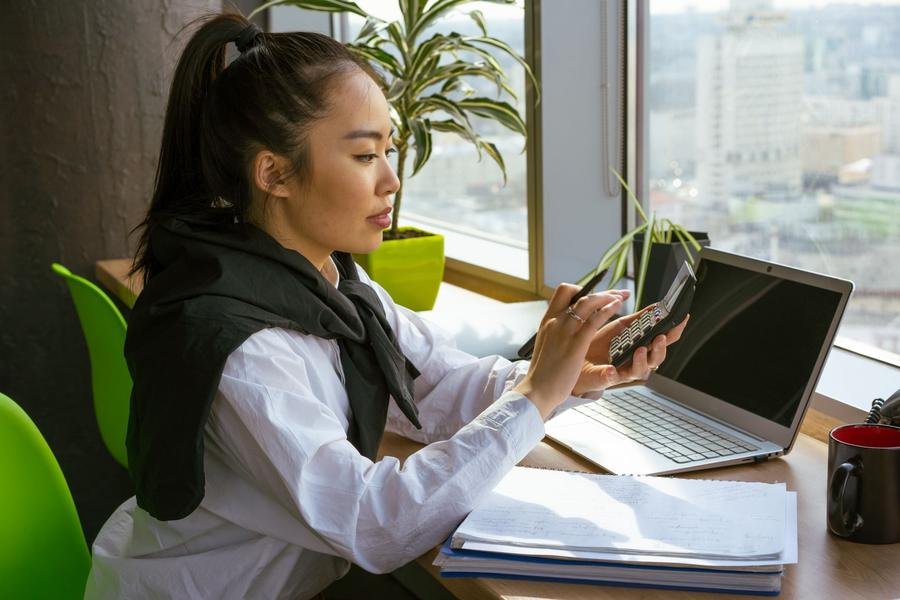UK accountant working through the books with a calculator at her desk