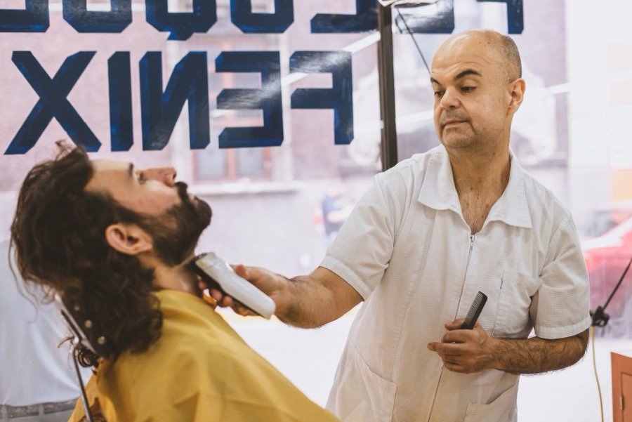 UK barber trimming a client's beard in a barbershop