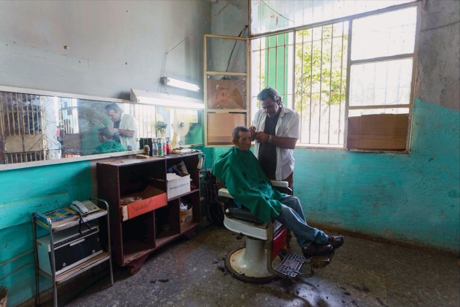 UK barber cutting an older client's hair in a traditional barbershop