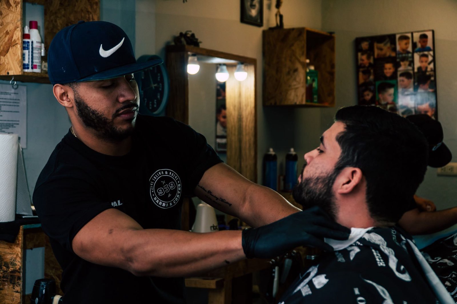 UK barber cutting a client's hair in a busy barbershop