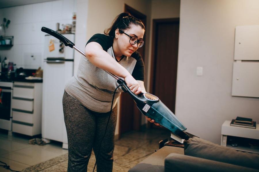 UK cleaner vacuuming a living room sofa