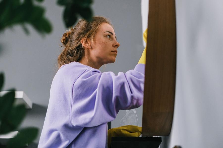 UK cleaner dusting furniture wearing rubber gloves