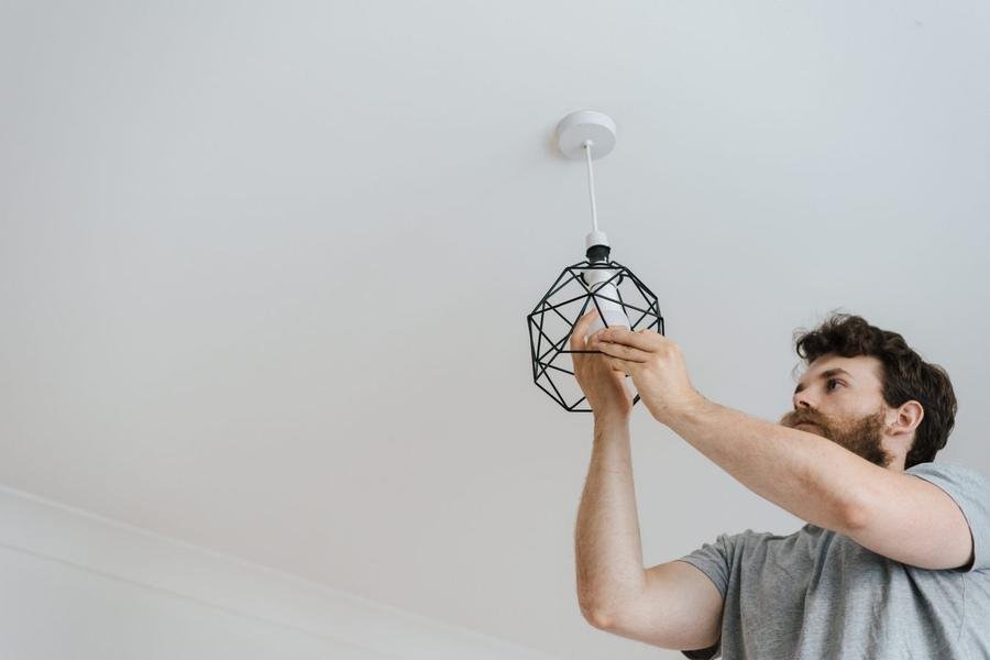 Electrician fitting a pendant light in a UK home