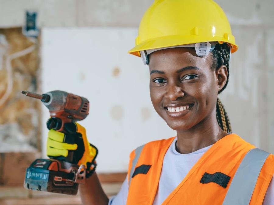 UK tradesperson in hi-vis holding a cordless impact driver on site