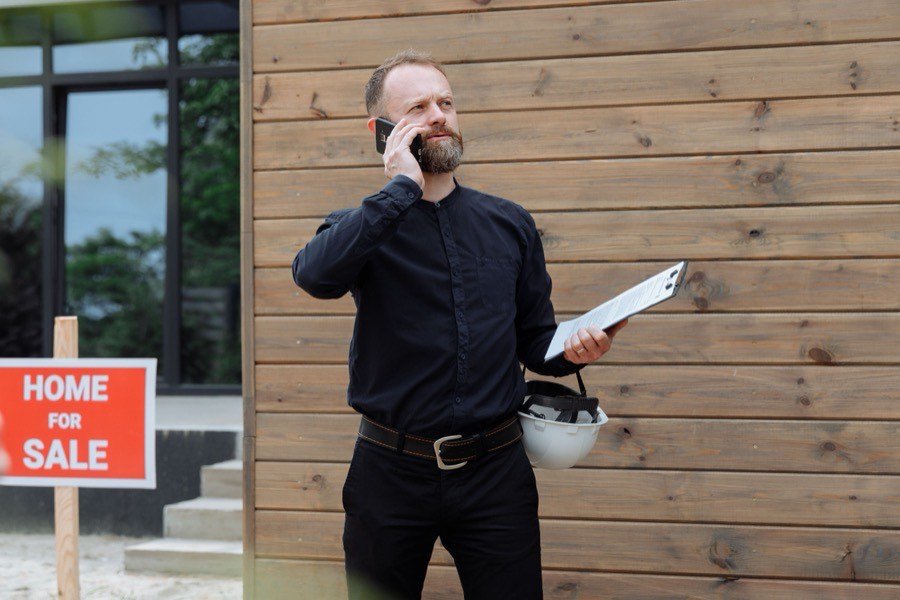 UK estate agent taking a call on a mobile outside a property for sale
