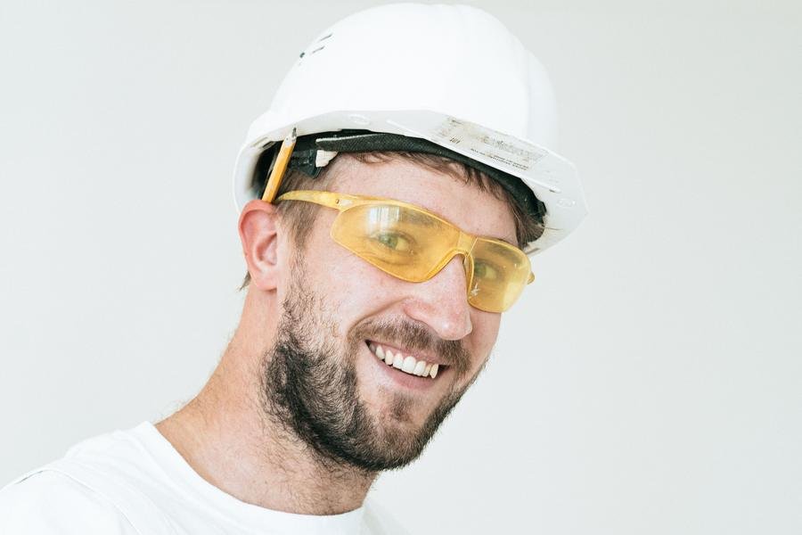 Smiling UK glazier in a hard hat and safety glasses on a job