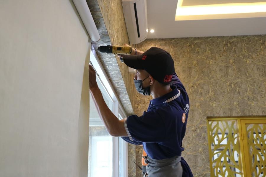 Glazier fitting a new window pane with a cordless drill