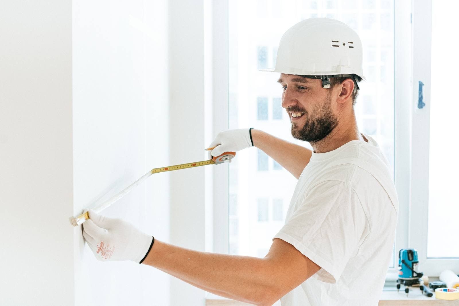 UK window fitter measuring up a window frame on a home installation