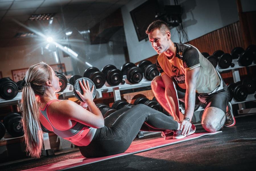 UK personal trainer guiding a client through a core workout in a gym