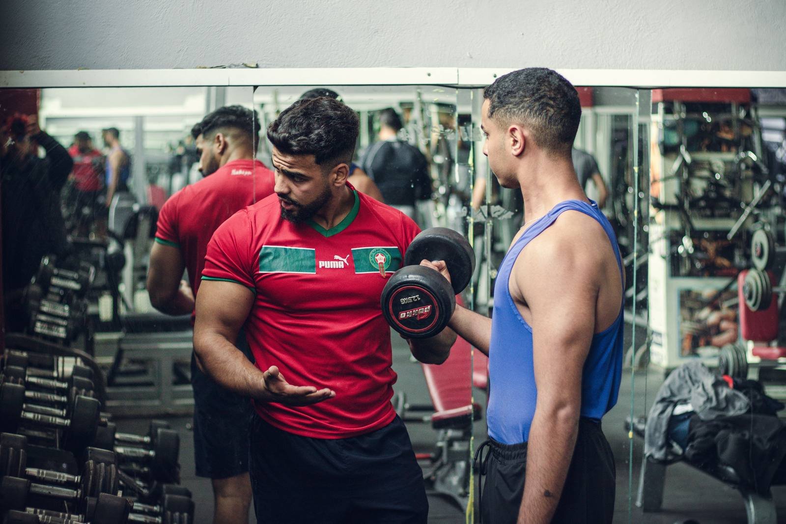 UK personal trainer coaching a client through a dumbbell workout in a gym