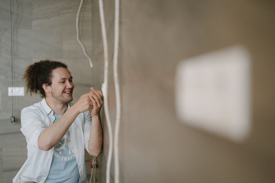 Heating engineer fitting a wall thermostat control in a UK home
