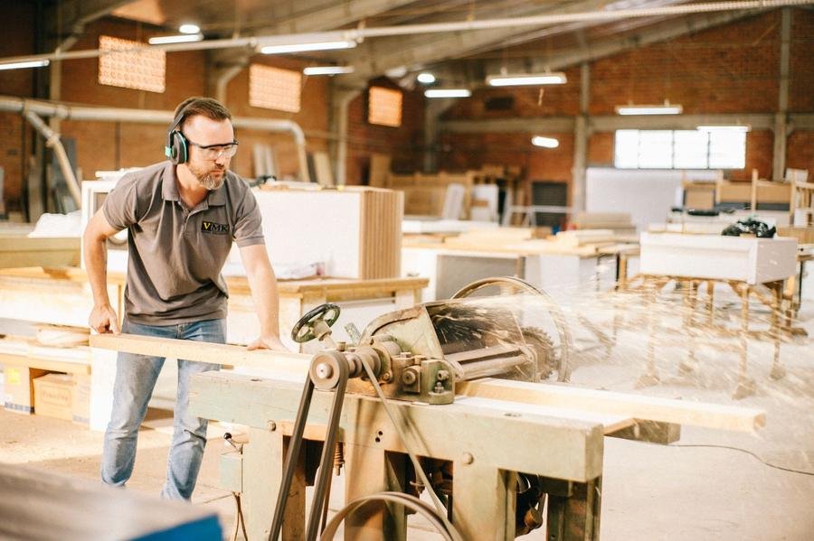 Kitchen fitter cutting timber for units in a UK workshop