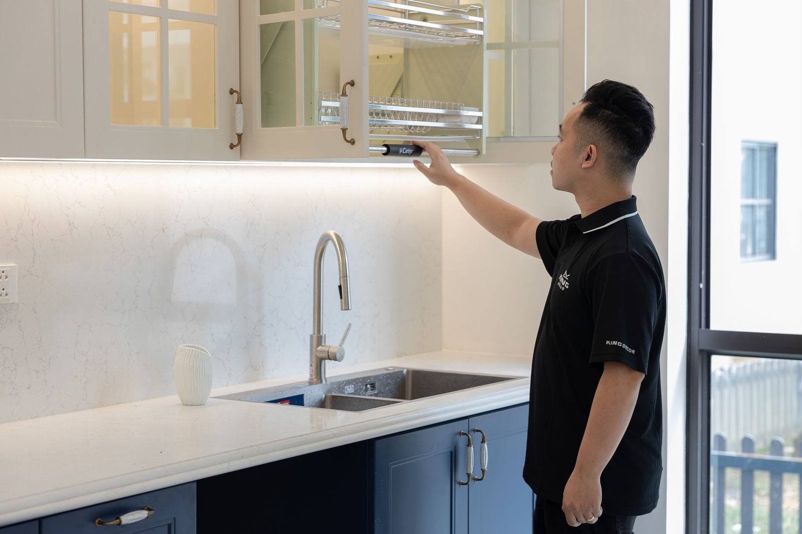 Kitchen fitter adjusting a wall cabinet in a newly installed UK kitchen