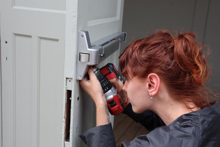 UK locksmith fitting a new lock to a door with a cordless drill