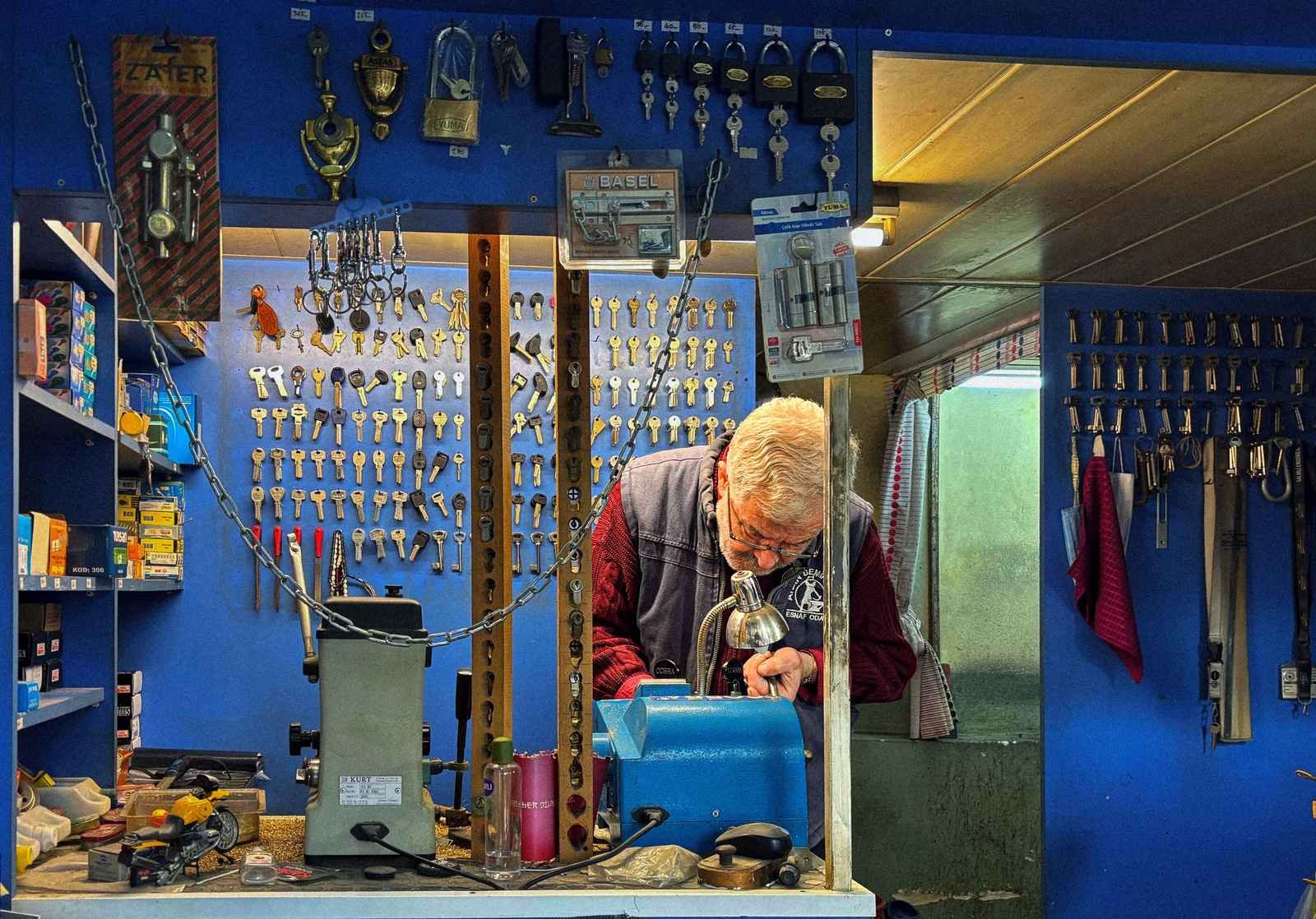 Experienced UK locksmith cutting a new key in his workshop surrounded by keys and locks