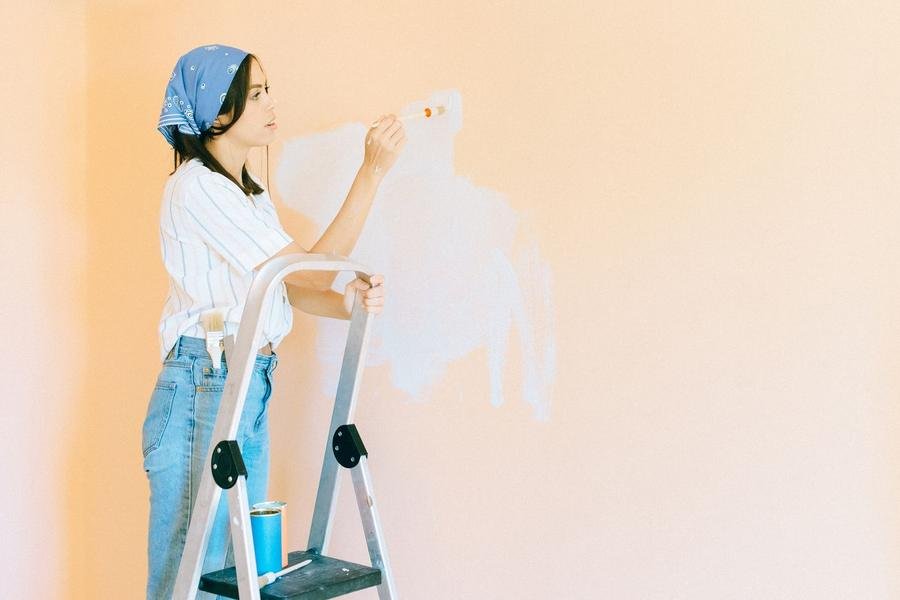 UK decorator on a step ladder painting a room