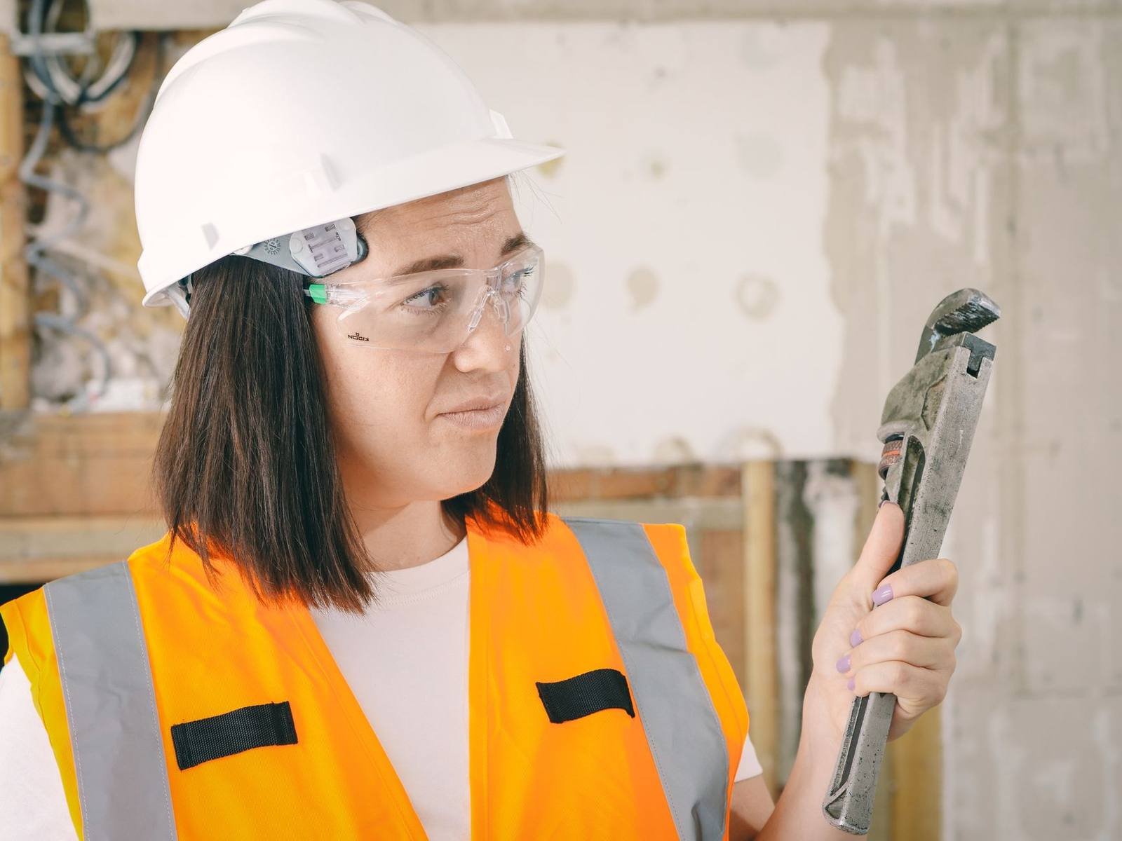 UK plumber in hi-vis holding a pipe wrench