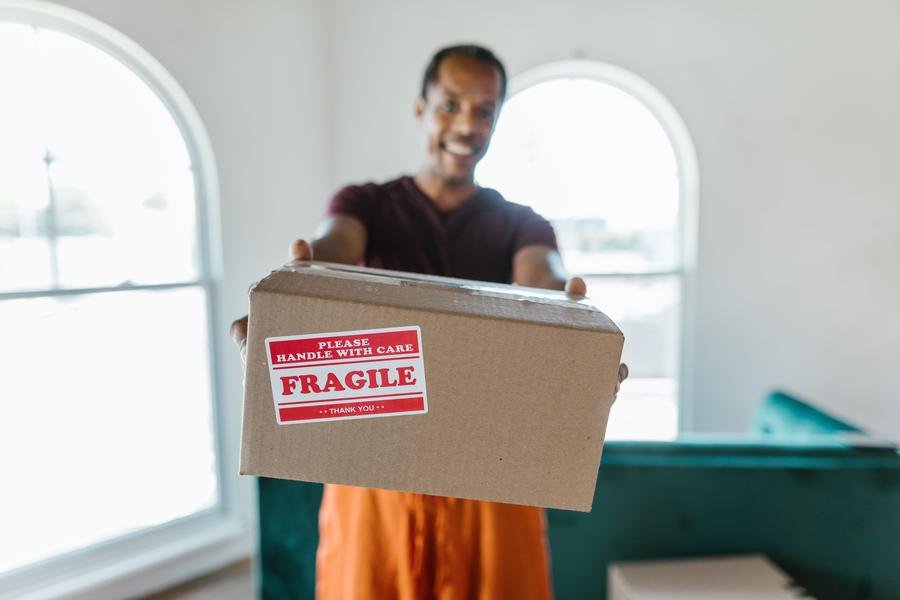 Smiling UK removals worker carrying a packed box