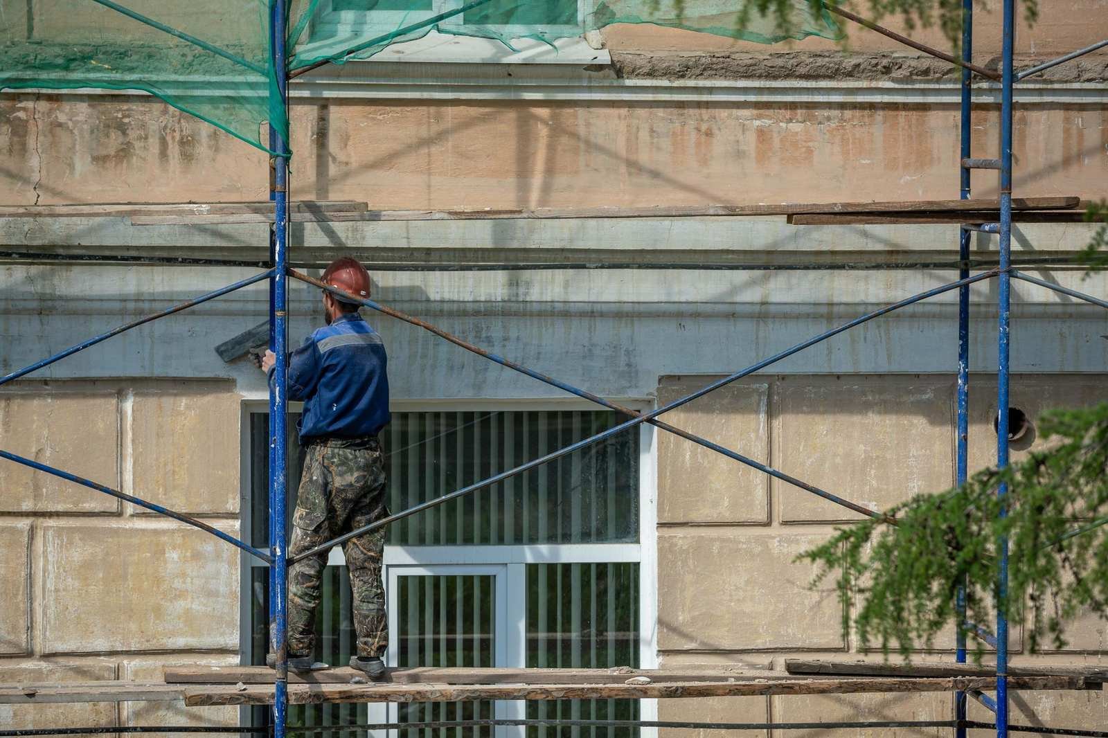 UK scaffolder working on a scaffold platform against a building facade
