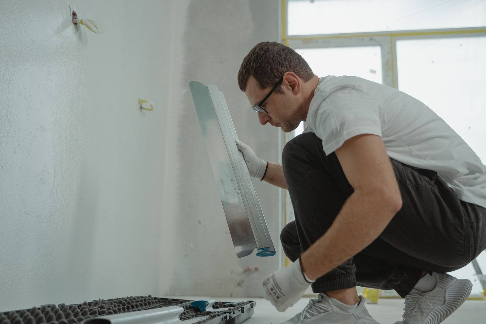 Tradesman in work gloves holding a wide finishing trowel